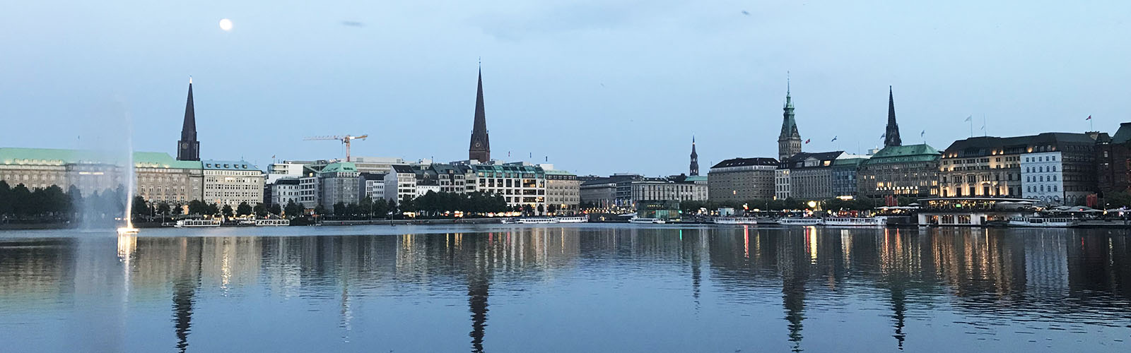 View of the Hamburg city skyline with a body of water in the foreground. It is nighttime.